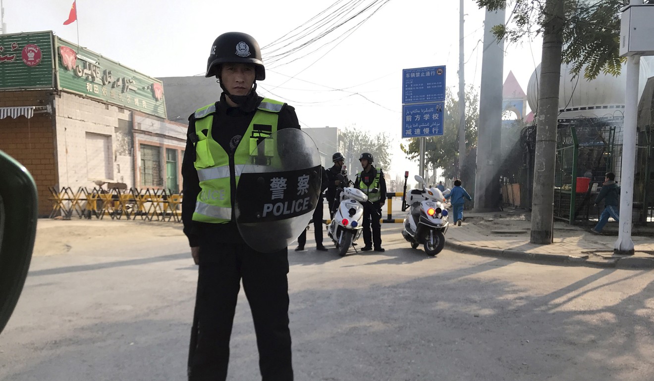 A police officer holds a shield as he guards a security post leading to a centre believed to be used for re-education in Korla, in western China's Xinjiang region. Photo: AP
