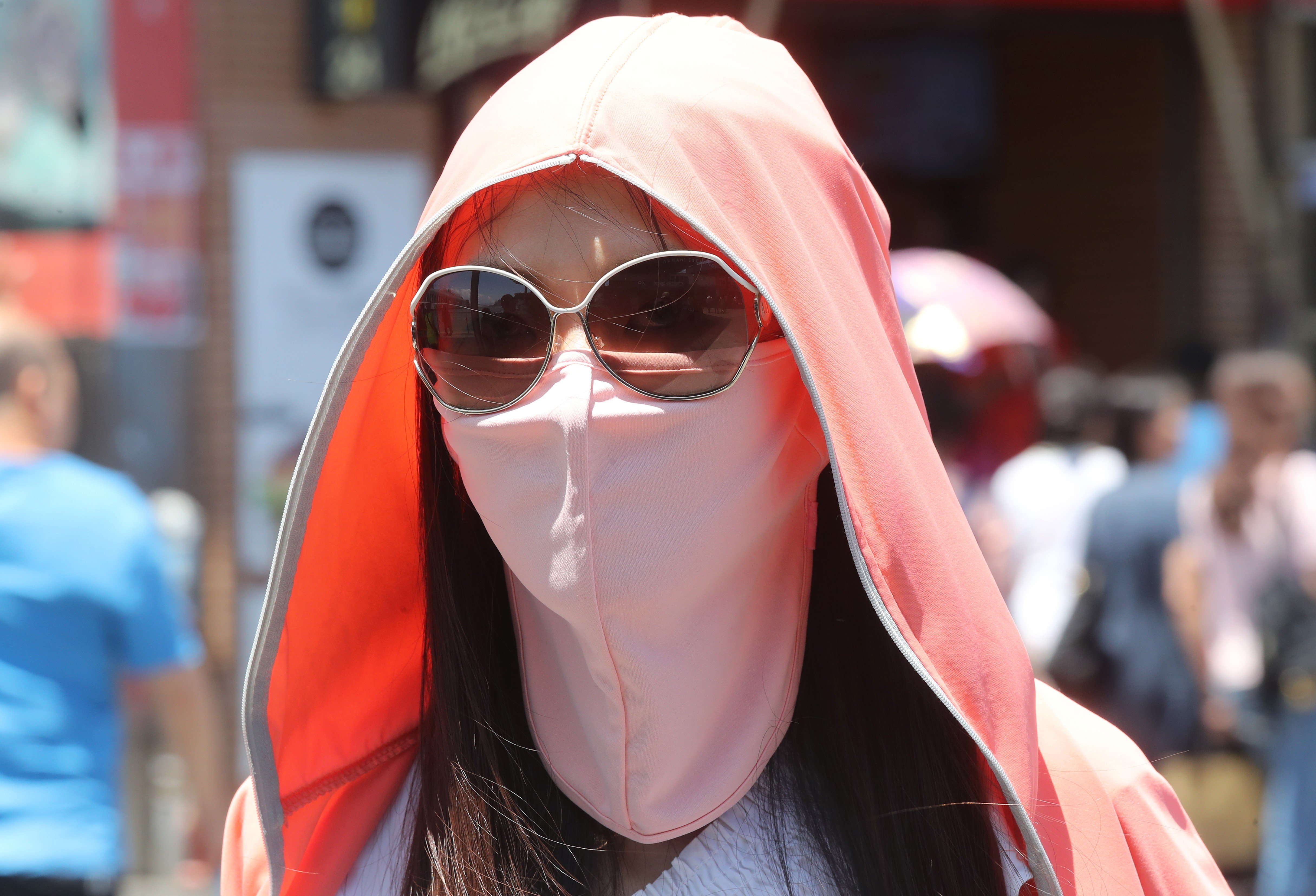 A woman covers up to protect herself from the sun in Tsim Sha Tsui, Hong Kong. Photo: K.Y. Cheng