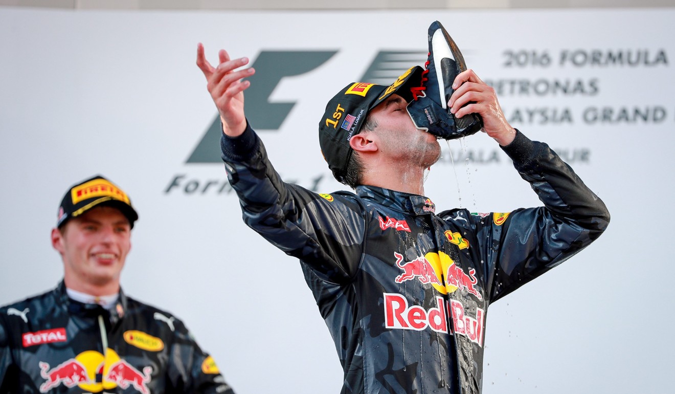 Second-placed finisher Max Verstappen (left) watches as his Red Bull teammate Daniel Ricciardo drinks champagne from his boot after winning the Malaysian Grand Prix in 2016. Photo: EPA