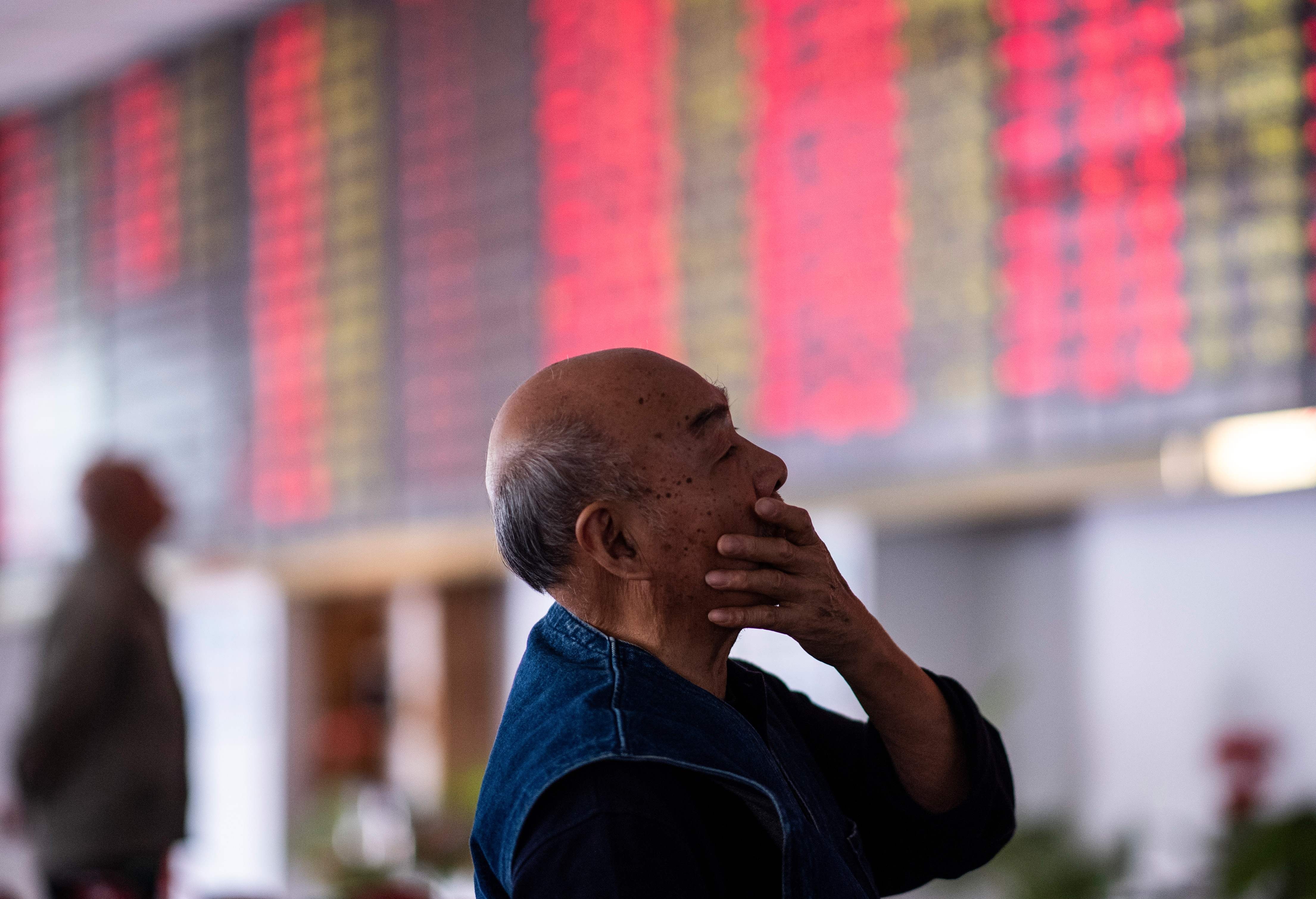 An investor looks at an electronic board showing stock information at a brokerage house in Shanghai on October 15. Photo: AFP