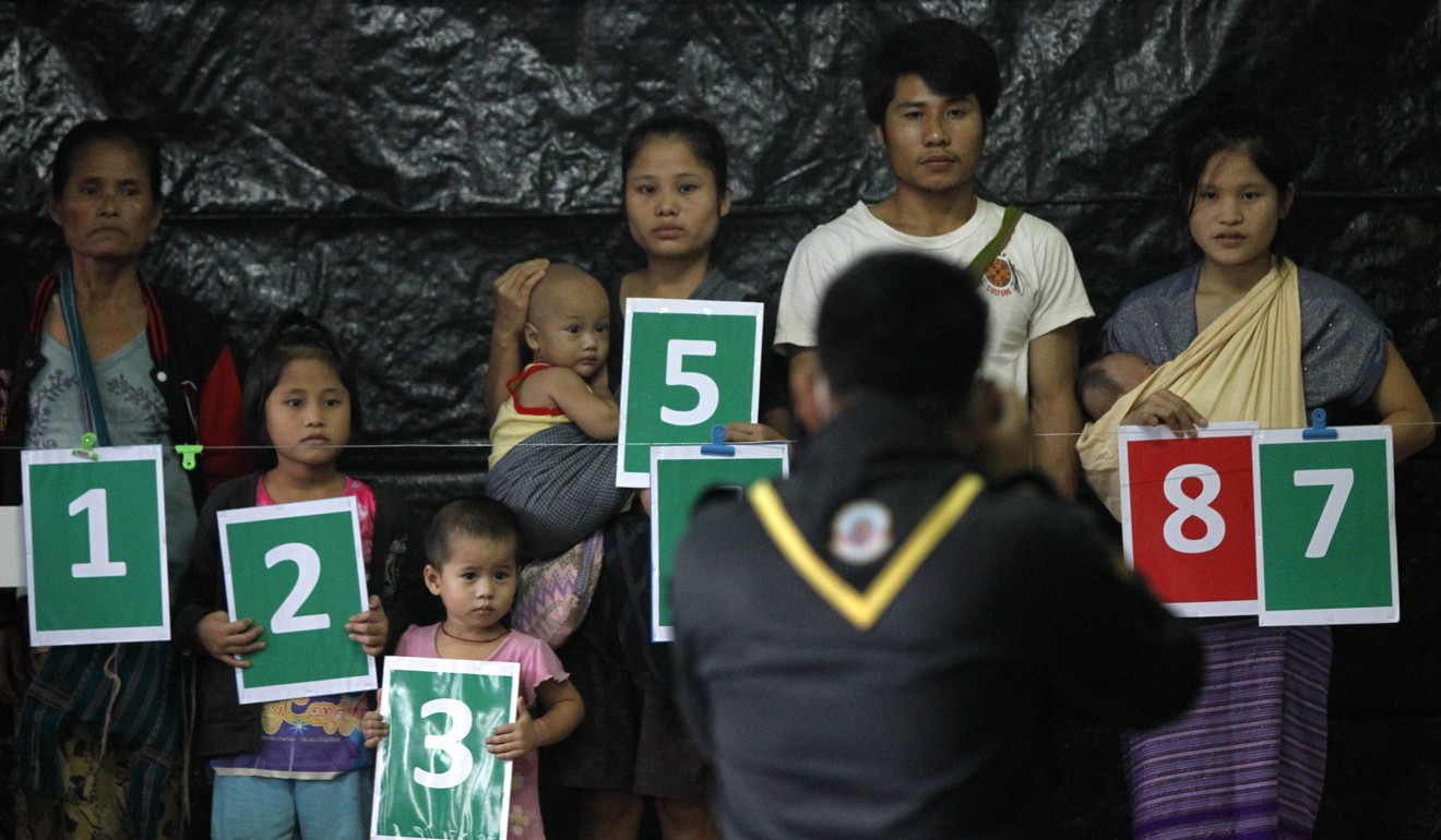 A refugee family hold numbered placards as they pose for a photo during a census conducted by the Thai authorities at a refugee camp near the Thailand-Myanmar border in 2014. Photo: Reuters.