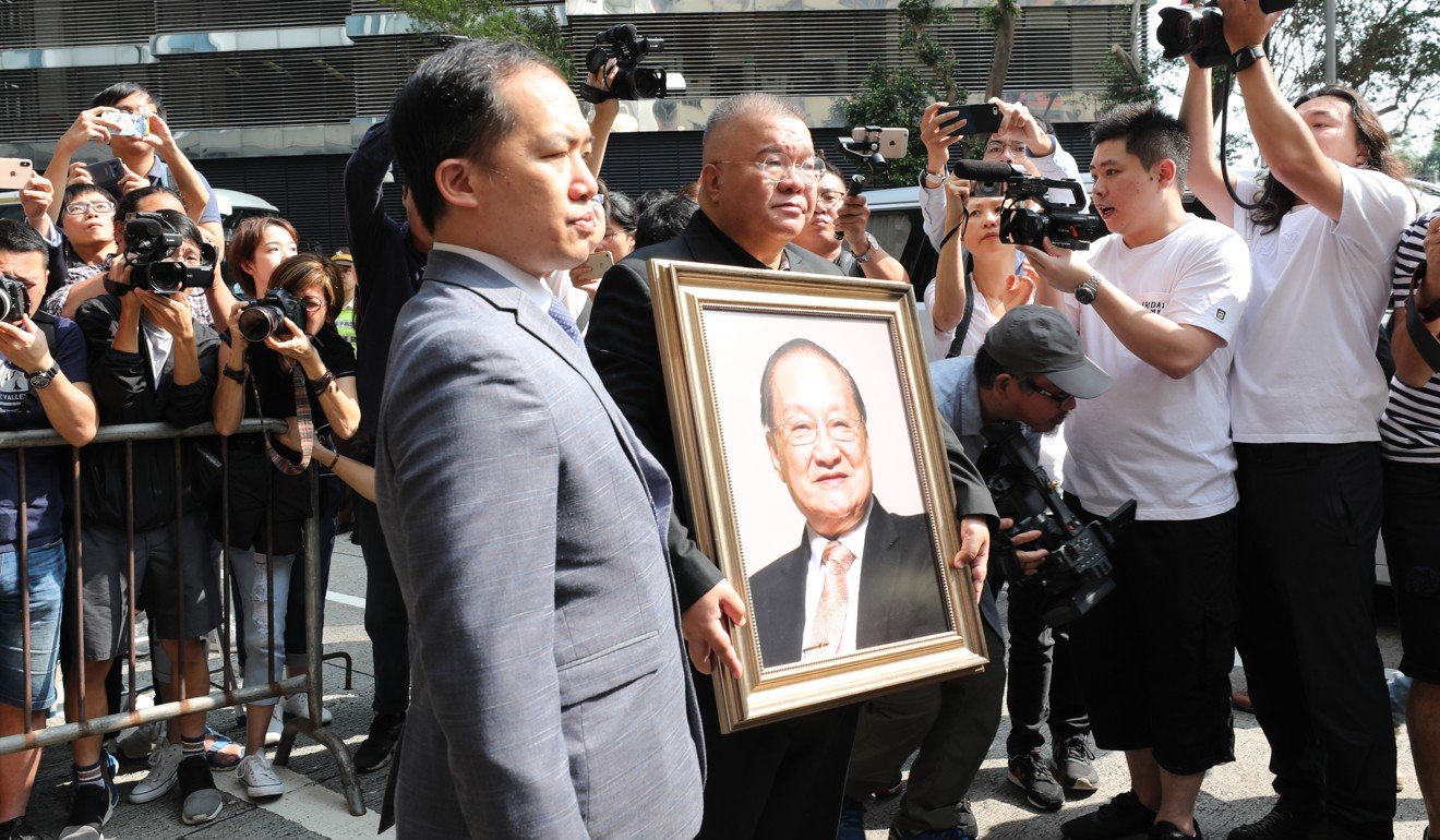 Andrew Cha holds a portrait of his father Louis Cha as he leaves Hong Kong Funeral Home in Quarry Bay on Tuesday morning. Photo: Felix Wong