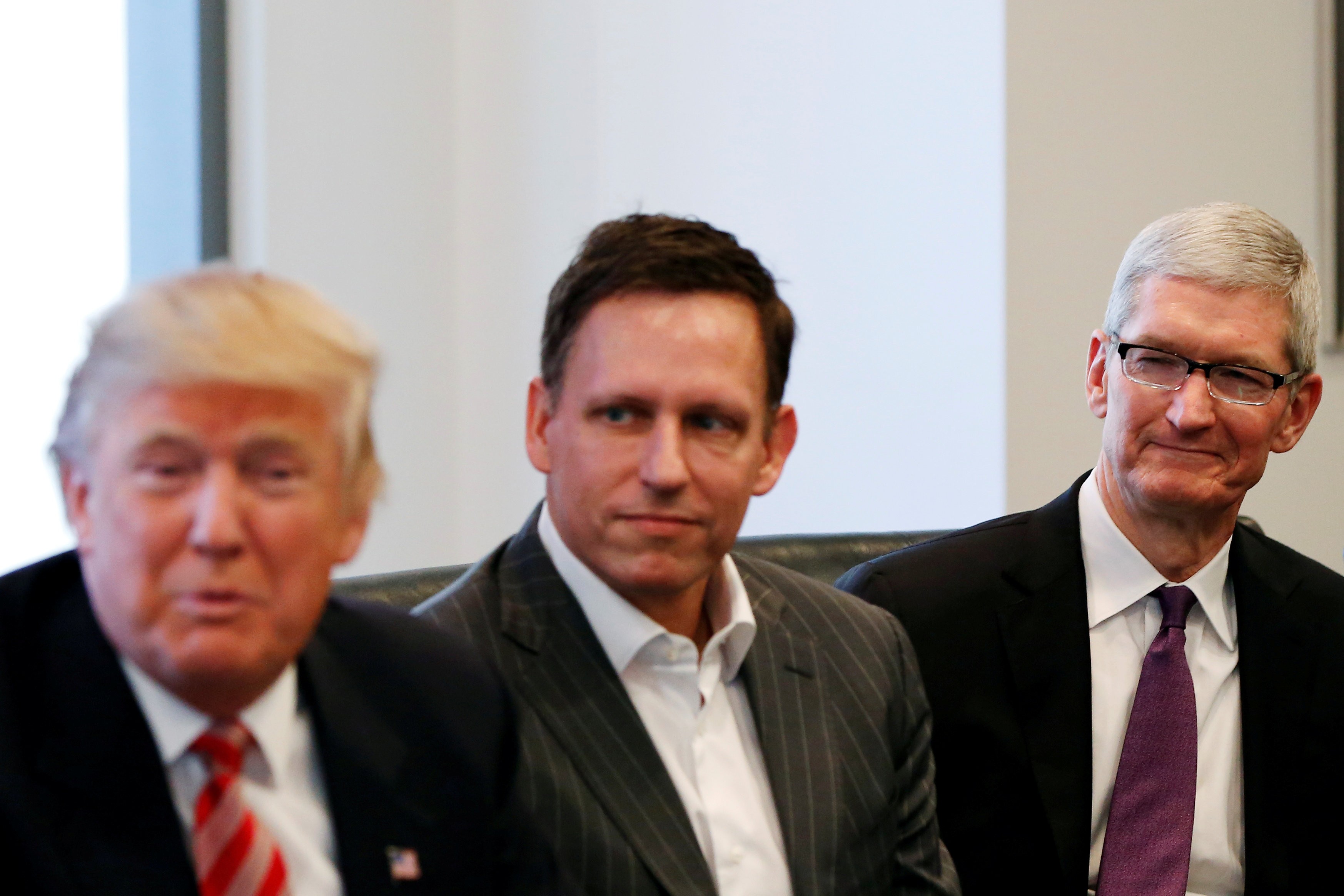 Then US president-elect Donald Trump speaks as PayPal co-founder Peter Thiel and Apple CEO Tim Cook look on during a meeting with technology leaders at Trump Tower in New York on December 14, 2016. Photo: Reuters