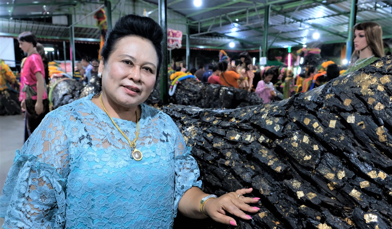 Wandee Khawkham, a woman who claims to be a medium, poses with one of the sacred boles she found on her property. Photo: Tibor Krausz