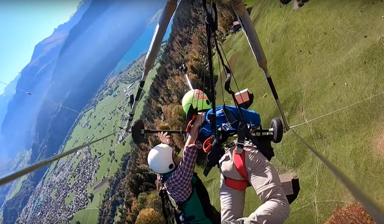 Florida man Chris Gursky (left) clings to his hang-gliding pilot in a video of his wild ride in Switzerland. Photo: Chris Gursky / YouTube