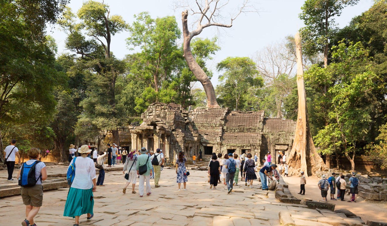 Tourists approach the Ta Prohm temple at Angkor where Thuch Salik and his younger brother help their mother, Mann Vanna, sell souvenirs. Photo: Alamy