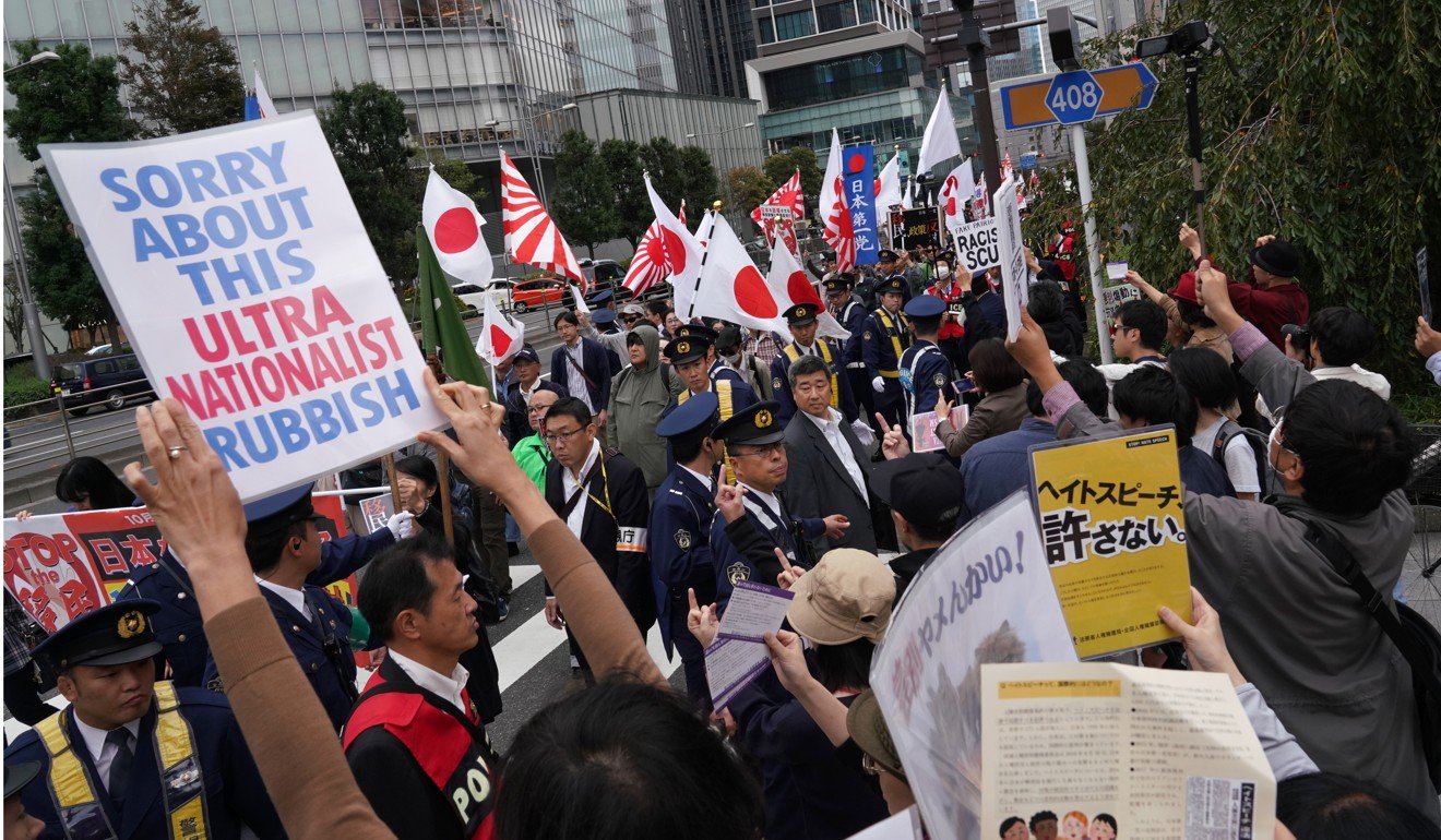 Demonstrators hold flags and placards as they march past counter-protesters during a rally against Japan Prime Minister Shinzo Abe’s labour law in October, 2018. Photo: Bloomberg