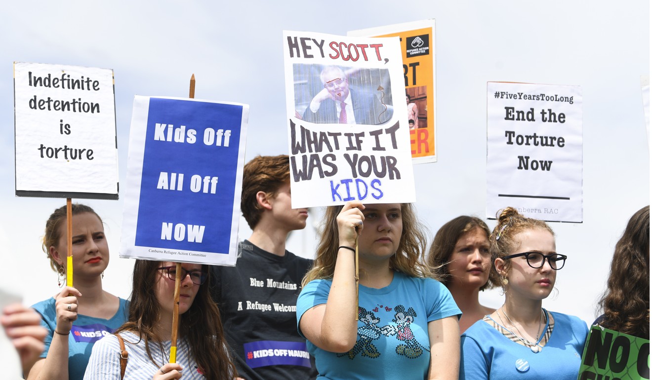 Protesters hold up signs demanding the resettlement of children held at the detention centres. Photo: EPA