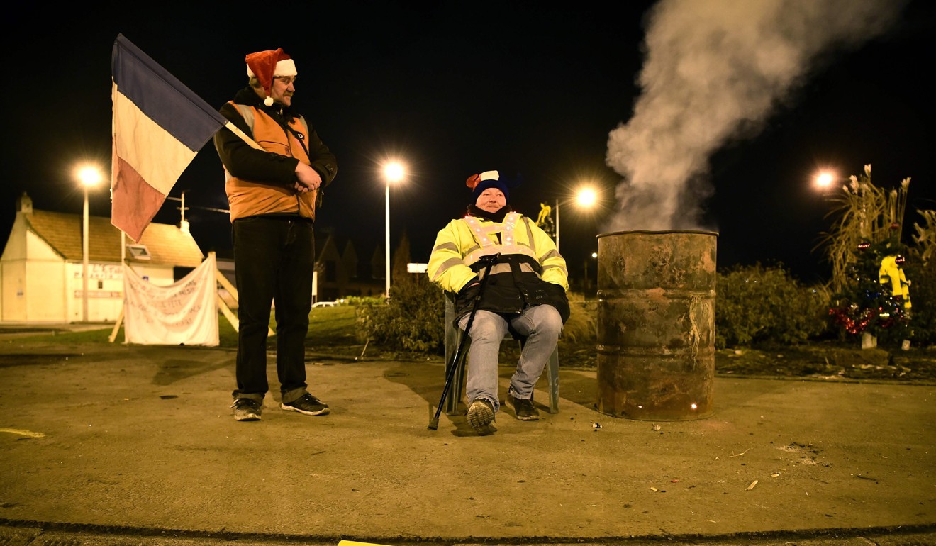 Yellow vest protestors stand near a sign saying ‘Thank you for honking’ on Christmas Eve at a roundabout in Somain, northern France. Photo: AFP