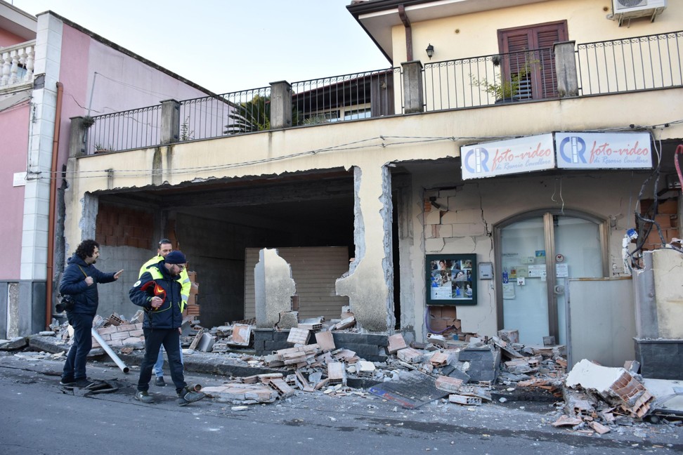 People walk past a heavily damaged house in Fleri, Sicily, on Wednesday. Photo: AP