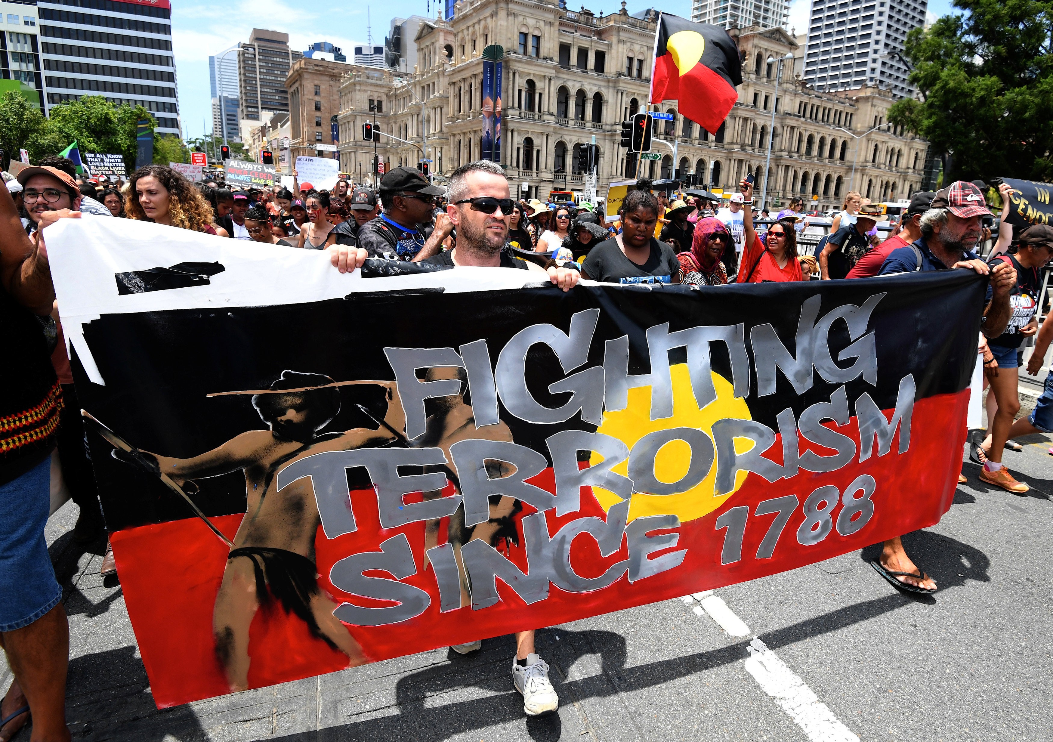 People hold signs and yell slogans as they join Aboriginal protesters in their march on Australia Day in central Brisbane on January 26, 2017. Photo: AAP