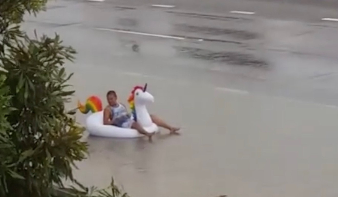 A man reclines on a unicorn float in floodwater on Bowen Road, Rosslea district, Townsville, Queensland. Photo: Nathan Hughes via Reuters