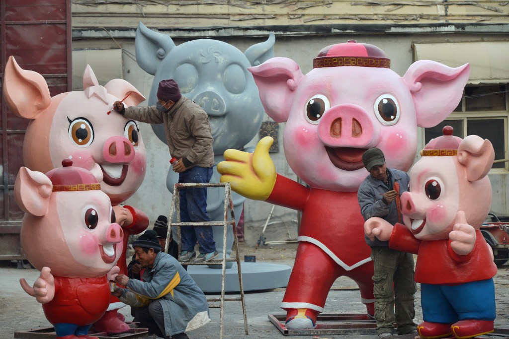 Men work on pig sculptures in preparation for the upcoming Lunar New Year of the Pig, in the Changping district of Beijing. Photo: Reuters