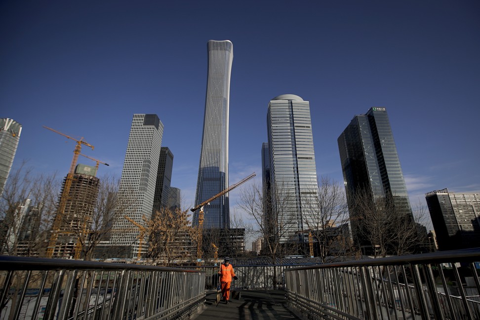 A cleaner walks on a pedestrian overpass against the skyscrapers under construction at the Central Business District in Beijing. Photo: AP