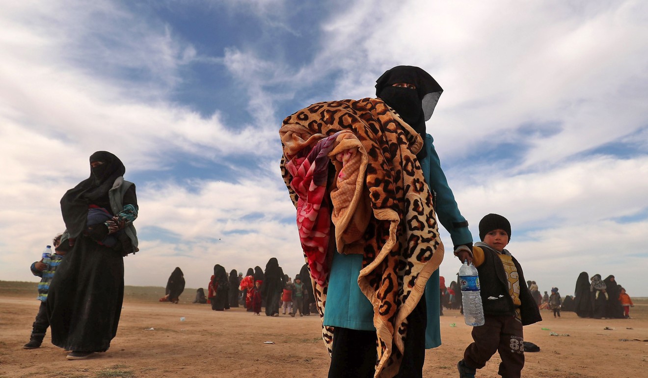 Fully veiled women walk with their children as civilians fleeing the Islamic State's group embattled holdout of Baghouz gather in a field on February 13, 2019 during an operation by the US-backed Syrian Democratic Forces (SDF) to expel the Islamic State group from the area, in the eastern Syrian province of Deir Ezzor. Photo: AFP