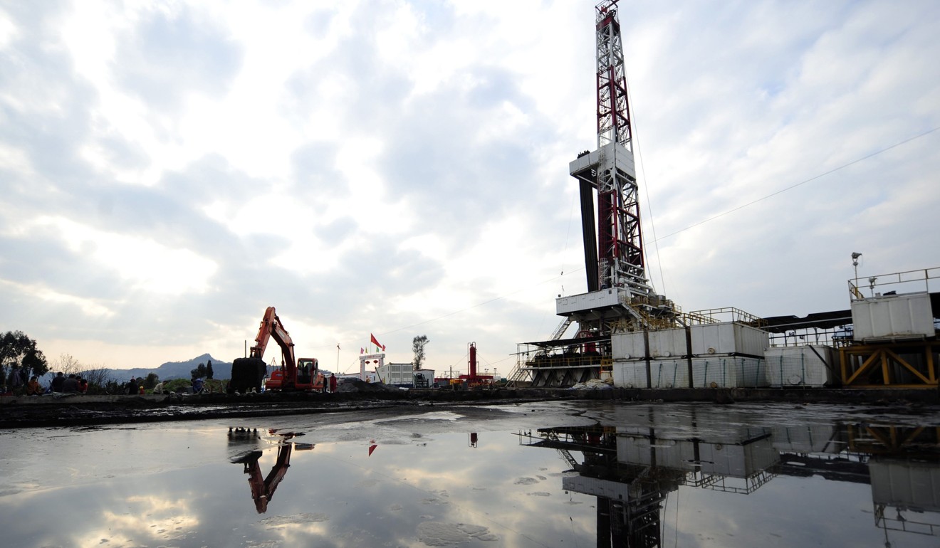 Work on a natural gas appraisal well goes on behind a pond of drilling waste in Sichuan province. Photo: Reuters