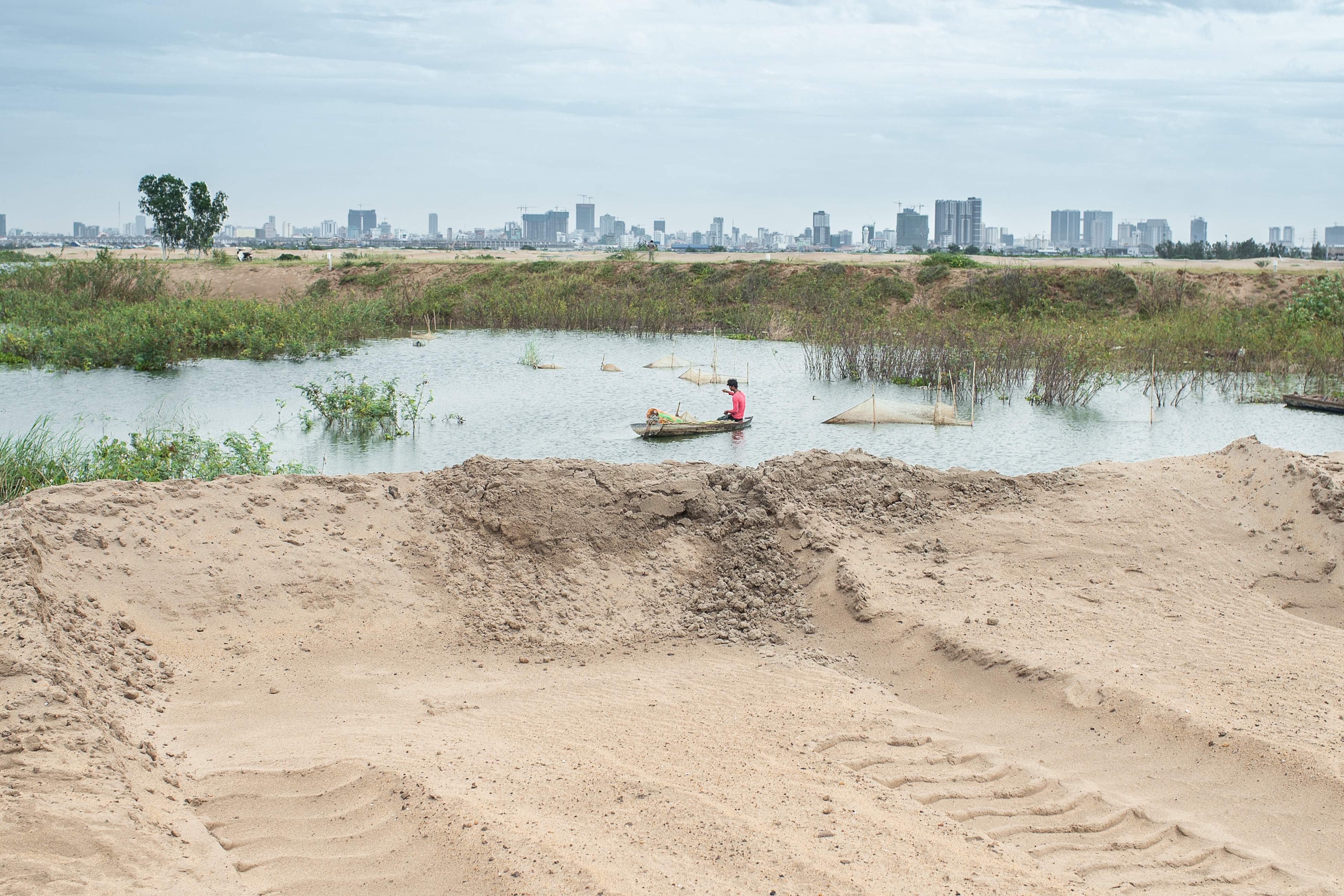 A young man trying to fish in Boeung Tompun next to a recent sand filled site in Phnom Penh. Photo: Enric Catala