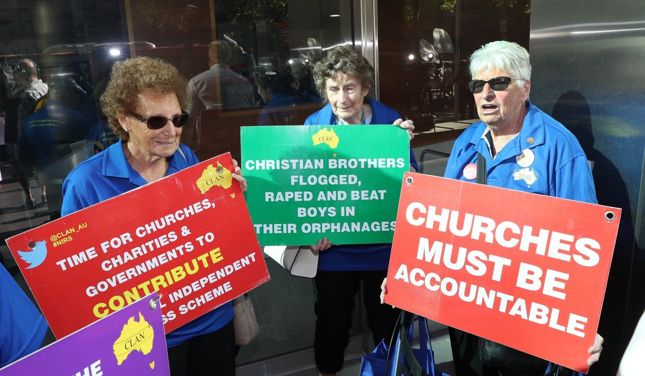 People hold placards as Cardinal George Pell arrives at County Court in Melbourne on Wednesday. Photo: EPA