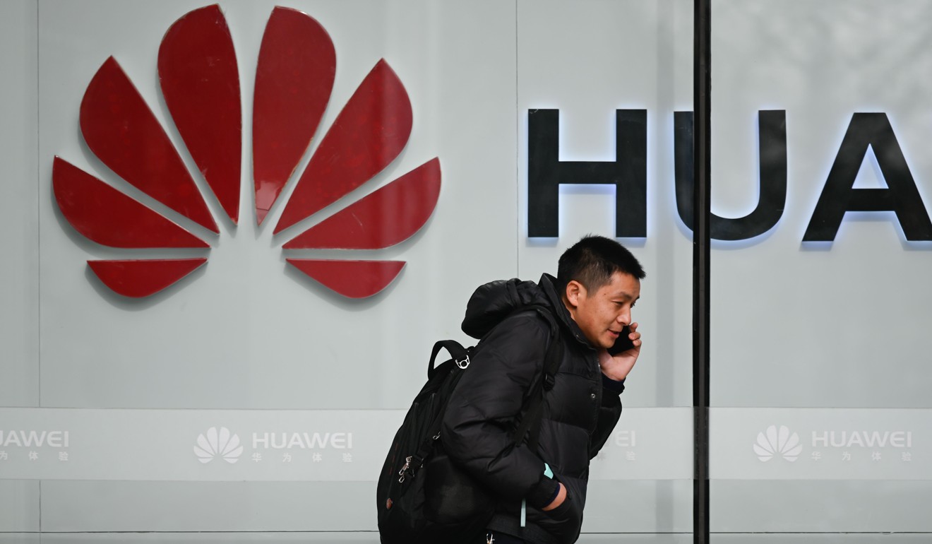A pedestrian talks on his phone while walking past a Huawei store in Beijing on January 30. Photo: AFP
