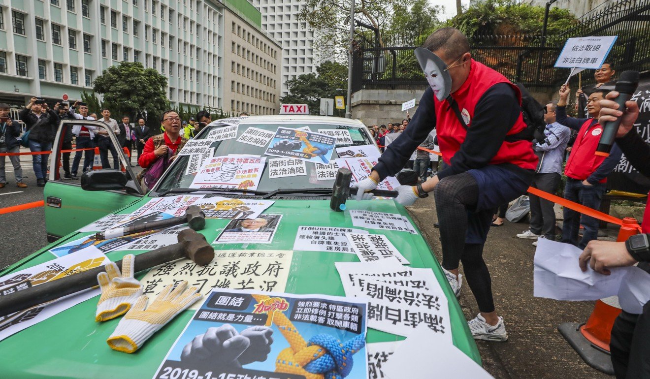 Taxi groups march and smash two cabs in a protest against illegal “white licence cars” and a proposed premium taxi scheme in January. Photo: Felix Wong
