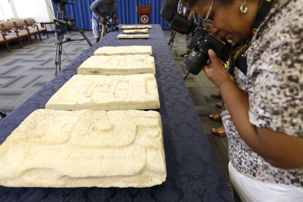  A woman photographs four ancient Mayan stelae that were returned to Belize by the US government.