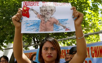 A protester displays an caricature of Philippine President Rodrigo Duterte waving a Chinese flag during a protest in front of the Chinese consulate in Makati, Manila, in March against China's militarisation of disputed islands in the South China Sea. Photo: AP