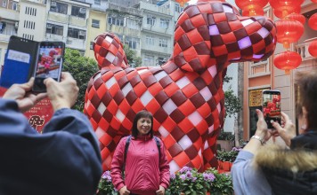 A woman is photographed next to an inflatable dog in Wan Chai on the second day of Lunar New Year. The Hang Seng Index rose by 36 per cent in 2017, a performance that it is unlikely to repeat this year. Photo: Dickson Lee