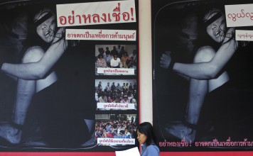 A woman walks past an anti-human trafficking campaign poster in Bangkok. Photo: AFP