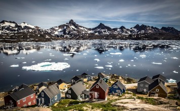 Houses in Tasiilaq at the edge of Kong Oskars Havn with the mountain Polheim in the background.