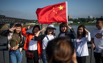 Chinese tourists taking pictures on the Broken Bridge in the border city of Dandong in Liaoning province. Photo: AFP