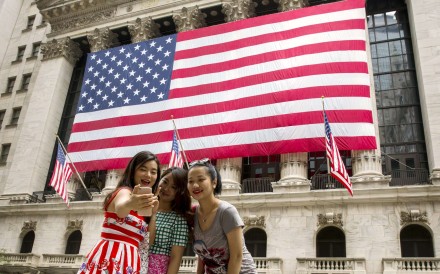 Chinese tourists take photos outside the New York Stock Exchange. Visa applications may get tougher for many mainlanders. Photo: Reuters