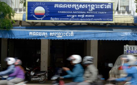 Motorbikes speed past the headquarters of the Cambodia National Rescue Party in Phnom Penh, Photo: AFP