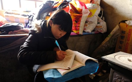 On weekends at home, 15-year-old Little Zhang sits on a tree stump to study, using a stool as a desk. Photo: Lea Li