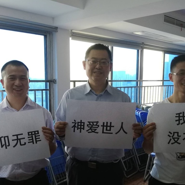 Early Rain Covenant Church pastor Wang Yi (centre) and fellow church members with signs which read: “Faith should not be criminalised”, “God loves all people in the world” and “We have no hatred”. Photo: Facebook
