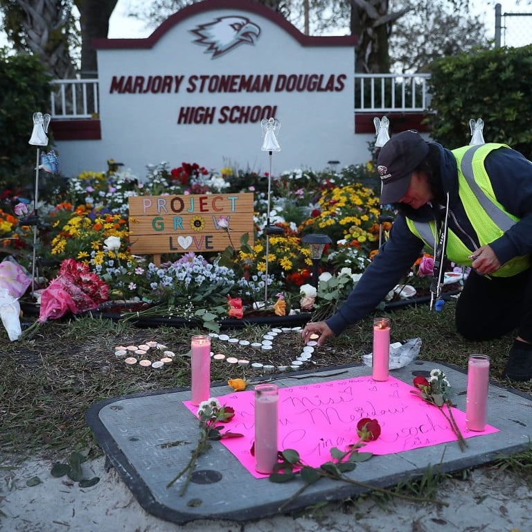 Wendy Behrend, a school crossing guard who was on duty one year ago when a shooter opened fire in Marjory Stoneman Douglas High School, pays her respects at a memorial to those killed on February 14, 2018, in Parkland, Florida. Photo: AFP