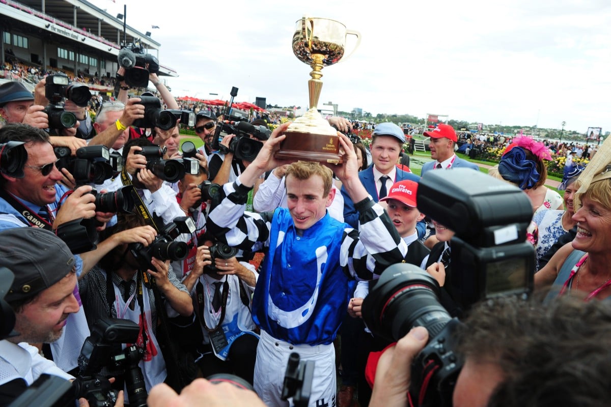 Ryan Moore holds the Melbourne Cup aloft after his win on Protectionist earlier this month. He will take the rides on Ambitious Dragon in the Hong Kong Mile and Golden Harvest in the Hong Kong Sprint. Photo: Kenneth Chan