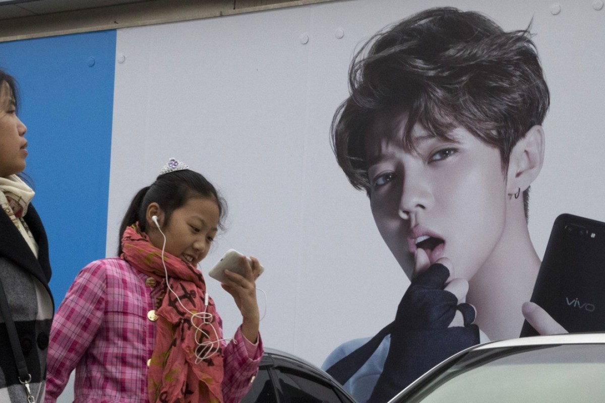 Chinese millennials walk past advertisement featuring teen idol Lu Han, also known as China's Justin Bieber in Beijing Photo: AP